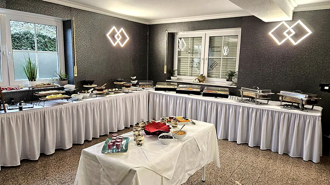 Festlich eingedeckter Saal mit langem Brunchbuffet und Desserttisch