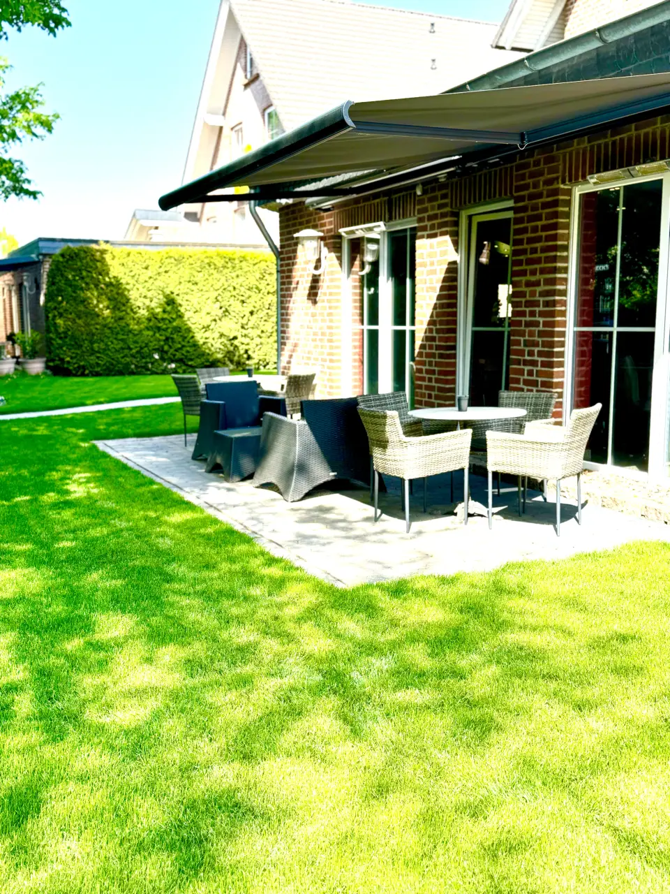 Terrasse des Duo Café mit Markise, Rattanmöbeln und Rasen