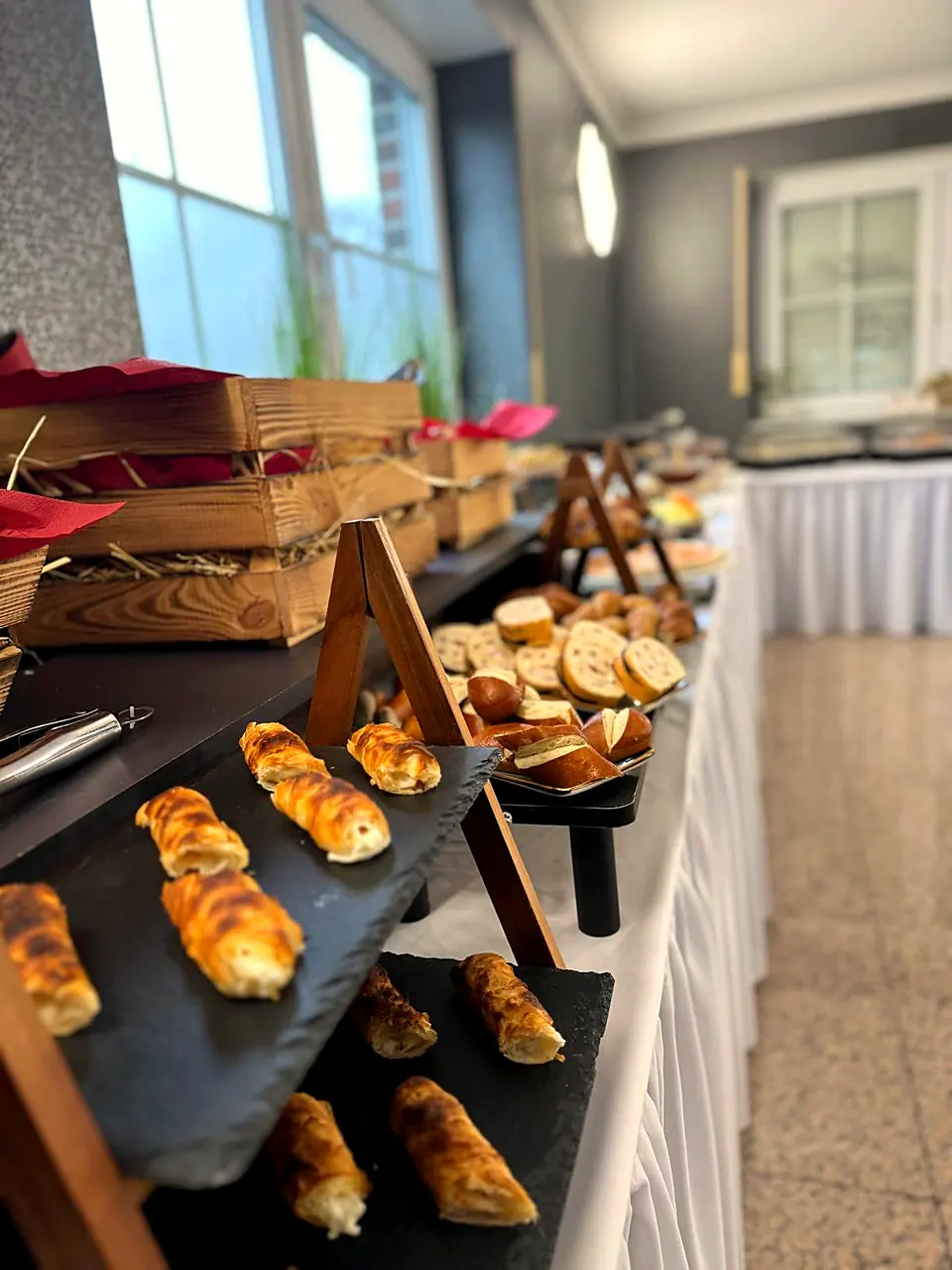 Herzhafte Blätterteigröllchen und Brötchen auf Schieferplatten
