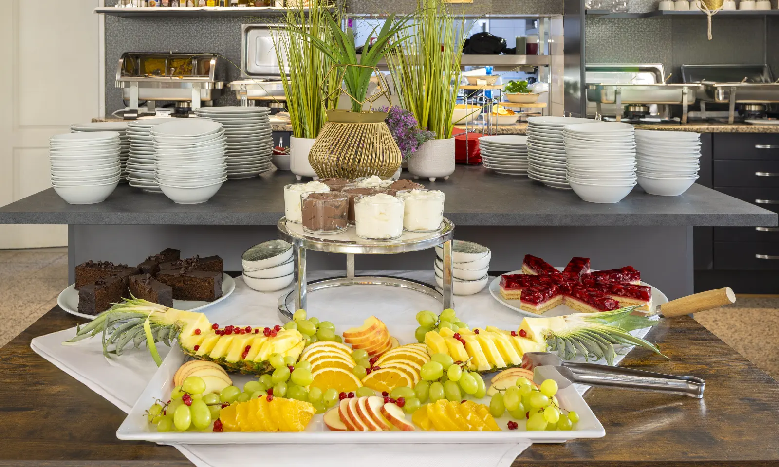 Brunchbuffet mit frischem Obst, Ananas, Trauben, Kuchen und Desserts im Gastraum