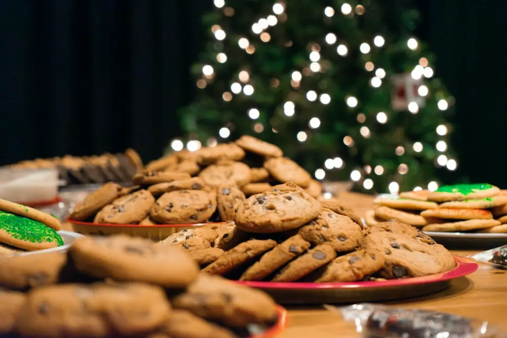 Weihnachtsgebäck auf dem Buffet vor einem beleuchteten Tannenbaum